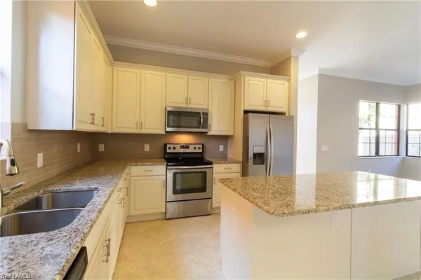 a kitchen with granite countertop a sink stainless steel appliances and cabinets