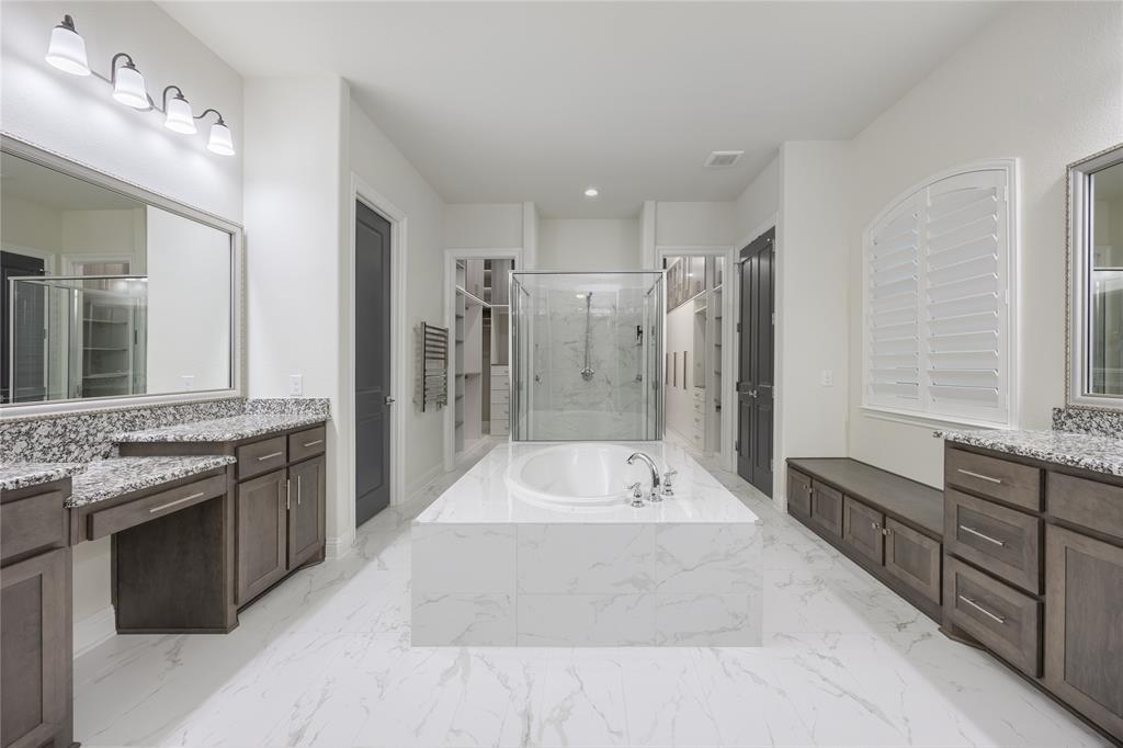 918 Sydney Lane Allen, TX 75013 - Photo 15 of 40 The property features a spacious bathroom with white walls, white marbled flooring, a built-in bathtub, a walk-in shower with glass enclosure, and dual vanity areas with granite countertops