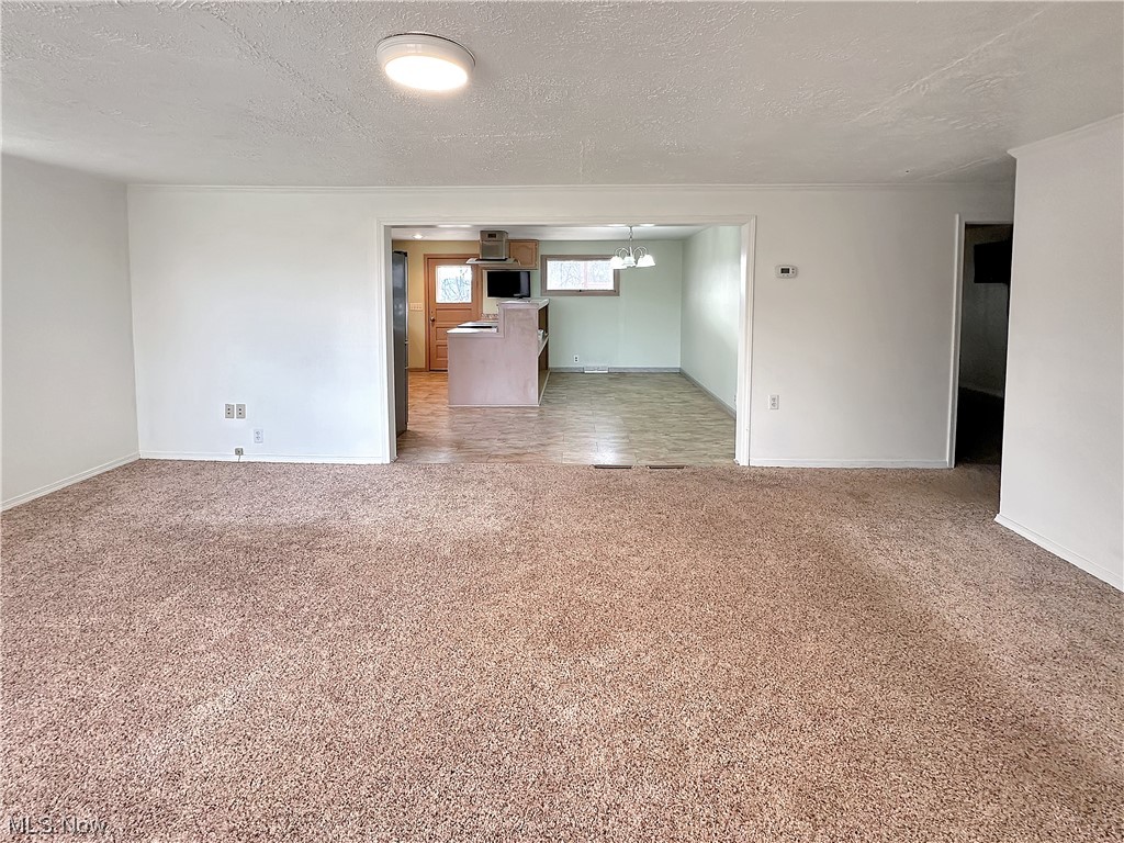 2692 Race Track Road New Cumberland, WV 26047 - Photo 8 of 25 Spare room with a textured ceiling, dark tile floors, and a notable chandelier