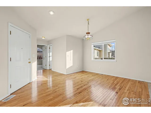 a view of an empty room with window and wooden floor
