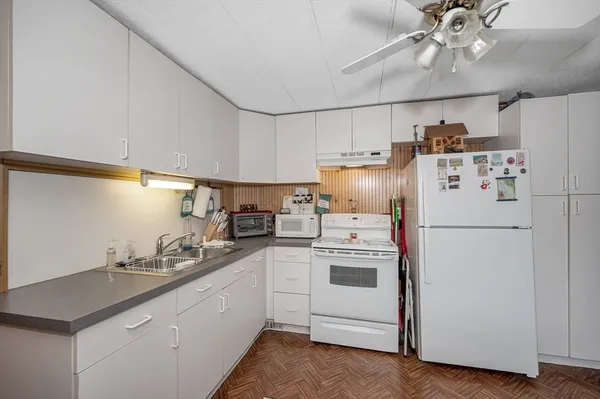 a kitchen with a sink a refrigerator and white cabinets