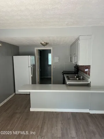 a view of a refrigerator in kitchen and empty room