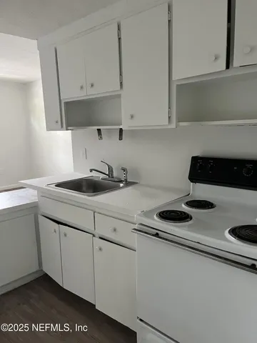 a kitchen with white cabinets and sink
