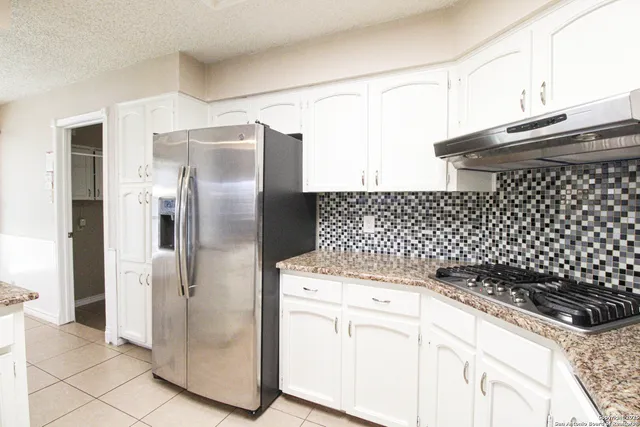 a kitchen with a refrigerator and a stove top oven