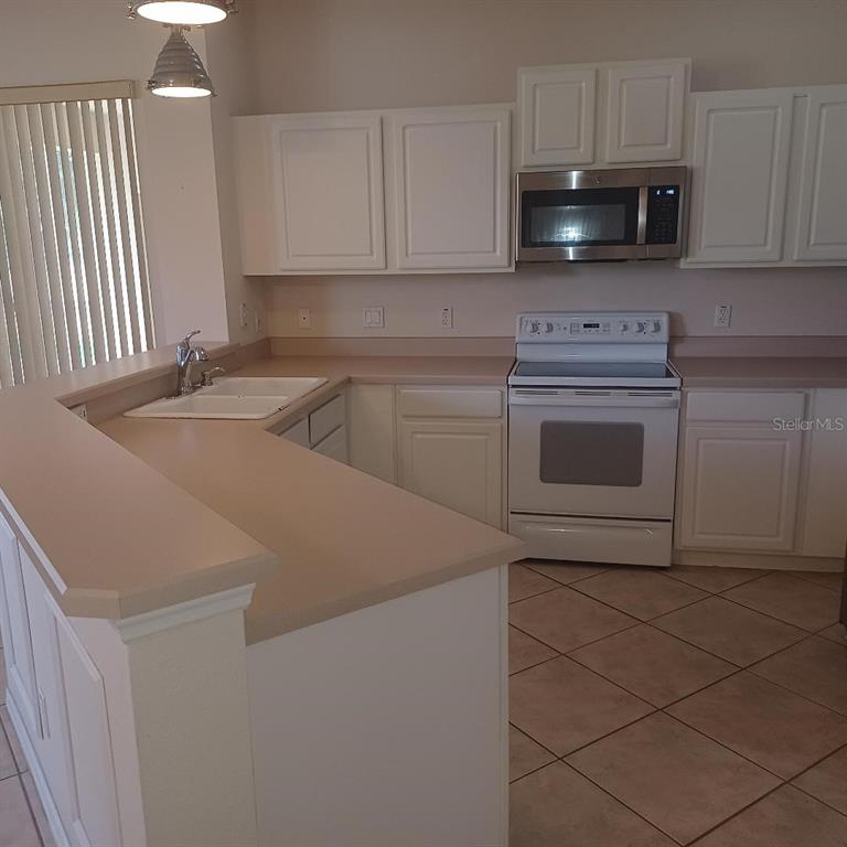 3807 Beacon Ridge Way Clermont, FL 34711 - Photo 7 of 15 a kitchen with stainless steel appliances granite countertop a sink a stove and microwave