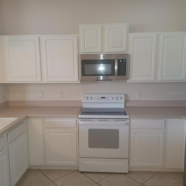 3807 Beacon Ridge Way Clermont, FL 34711 - Photo 9 of 15 a kitchen with white cabinets and white appliances