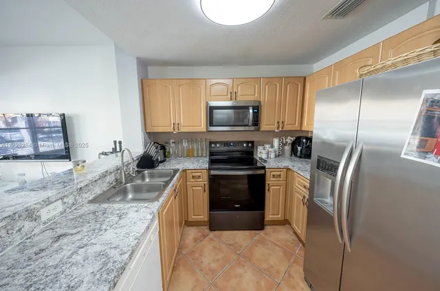 a kitchen with stainless steel appliances granite countertop a refrigerator a stove top oven a sink and dishwasher