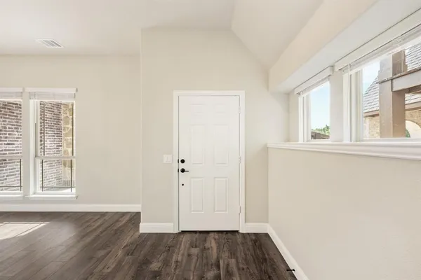 an empty room with wooden floor and windows