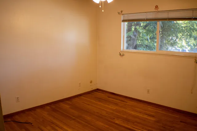 a view of empty room with wooden floor and fan