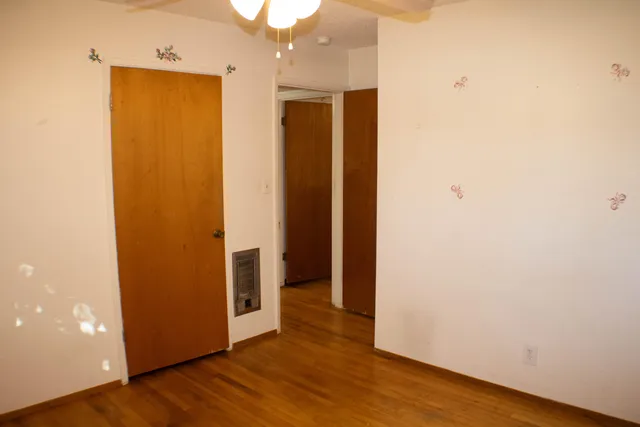 a view of an empty room with wooden floor and closet