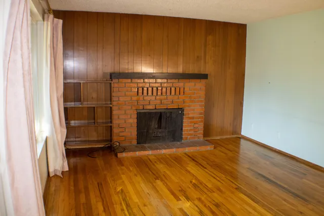 a view of a livingroom with wooden floor and a fireplace