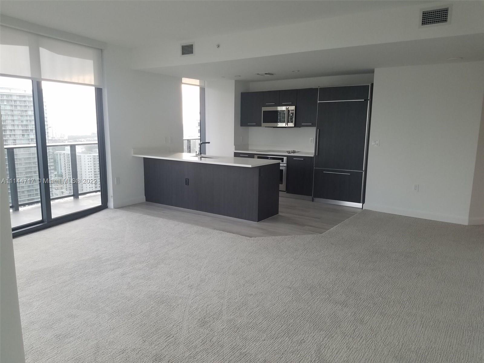 45 Southwest 9th Street, Unit 3103 Miami, FL 33130 - Photo 9 of 23 a kitchen with stainless steel appliances kitchen island granite countertop a refrigerator a sink a stove with wooden cabinets