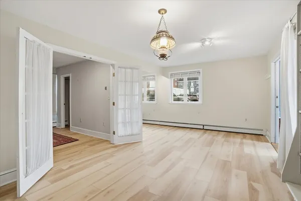 a view of an empty room with wooden floor and a window