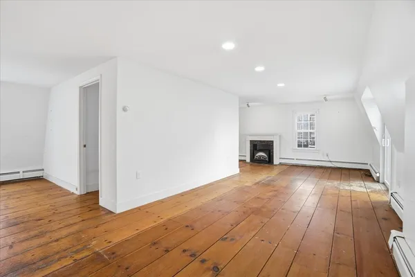 an empty room with wooden floor and fireplace