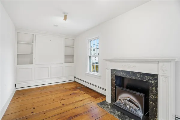 an empty room with wooden floor fireplace and windows