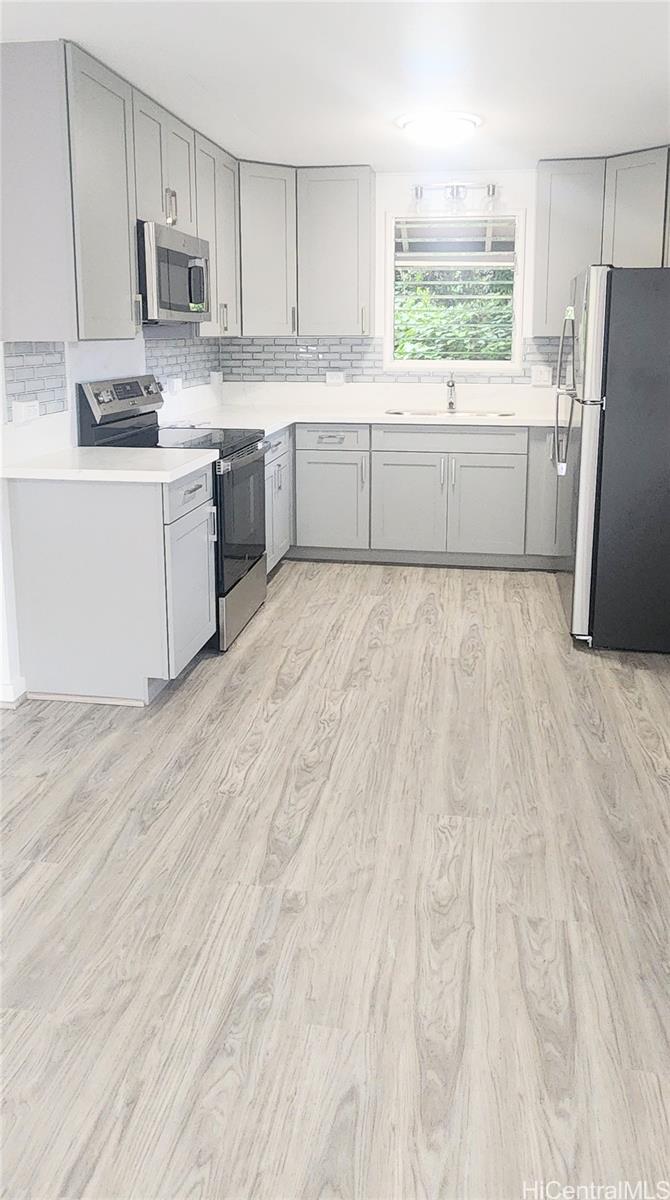 41-978B Waikupanaha Street, Unit B4 Waimanalo, HI 96795 - Photo 4 of 18 a kitchen with stainless steel appliances a refrigerator sink and microwave