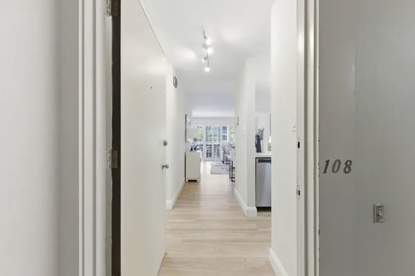 a view of a hallway with wooden floor and a bathroom