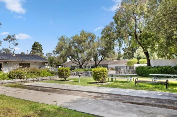 a sign board with flower plants and wooden fence
