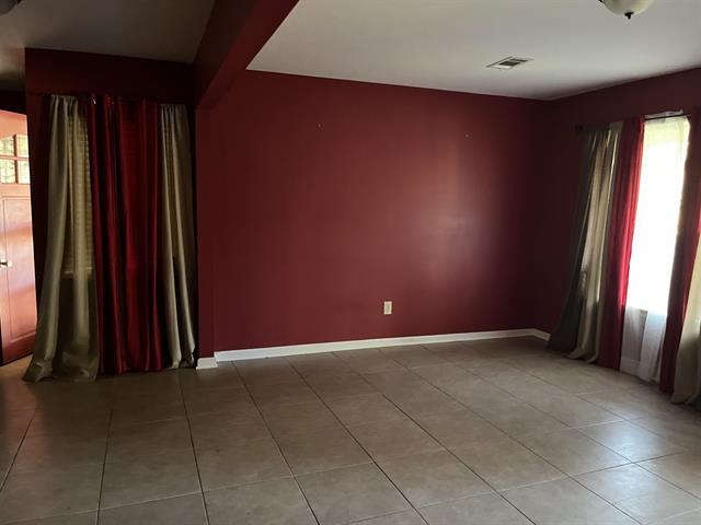 Unfurnished room featuring light tile patterned floors and baseboards