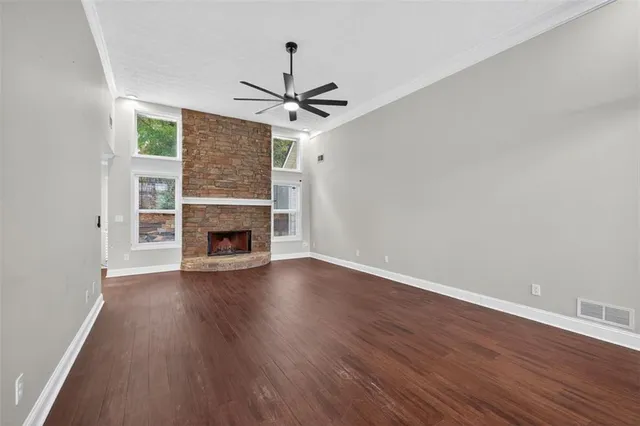 an empty room with wooden floor a fireplace a ceiling fan and wooden floor