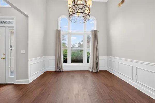 an empty room with wooden floor fan and windows