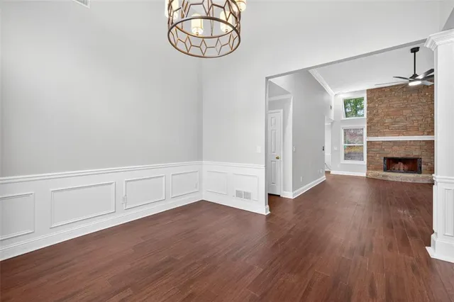 an empty room with wooden floor fireplace and windows