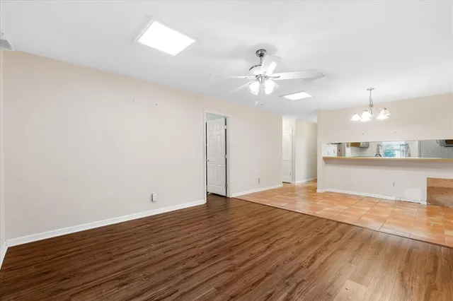a view of an empty room with wooden floor and a ceiling fan