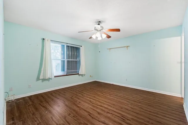 a view of an empty room with window and wooden floor