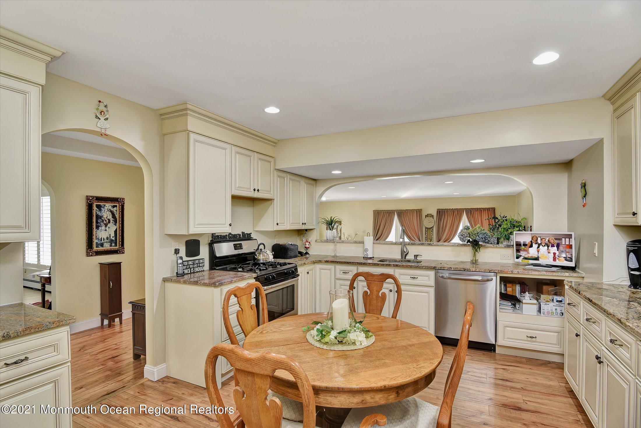 1995 Campbell Road Belmar, NJ 07719 - Photo 14 of 46 a kitchen with a stove a sink a kitchen island with chairs and wooden cabinets