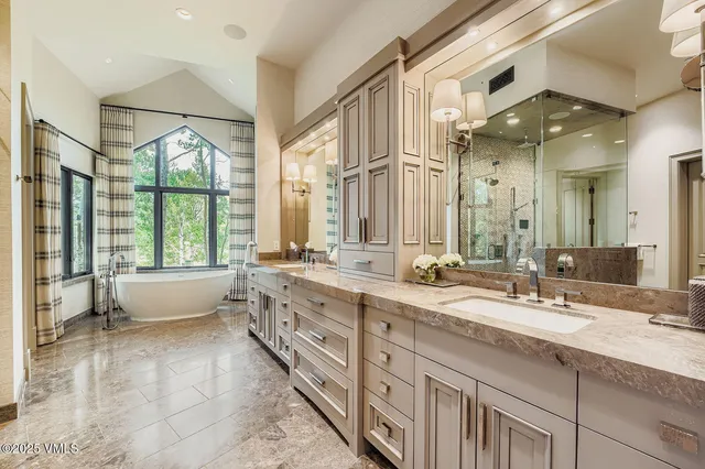 a spacious bathroom with a double vanity sink large mirror and a bathtub