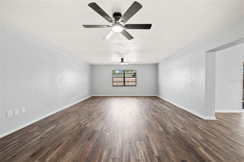 11215 Addison Street Spring Hill, FL 34609 - Photo 11 of 51 an empty room with wooden floor chandelier fan and windows