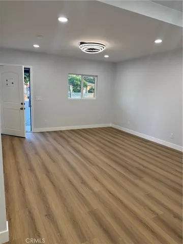 an empty room with wooden floor a ceiling fan and windows