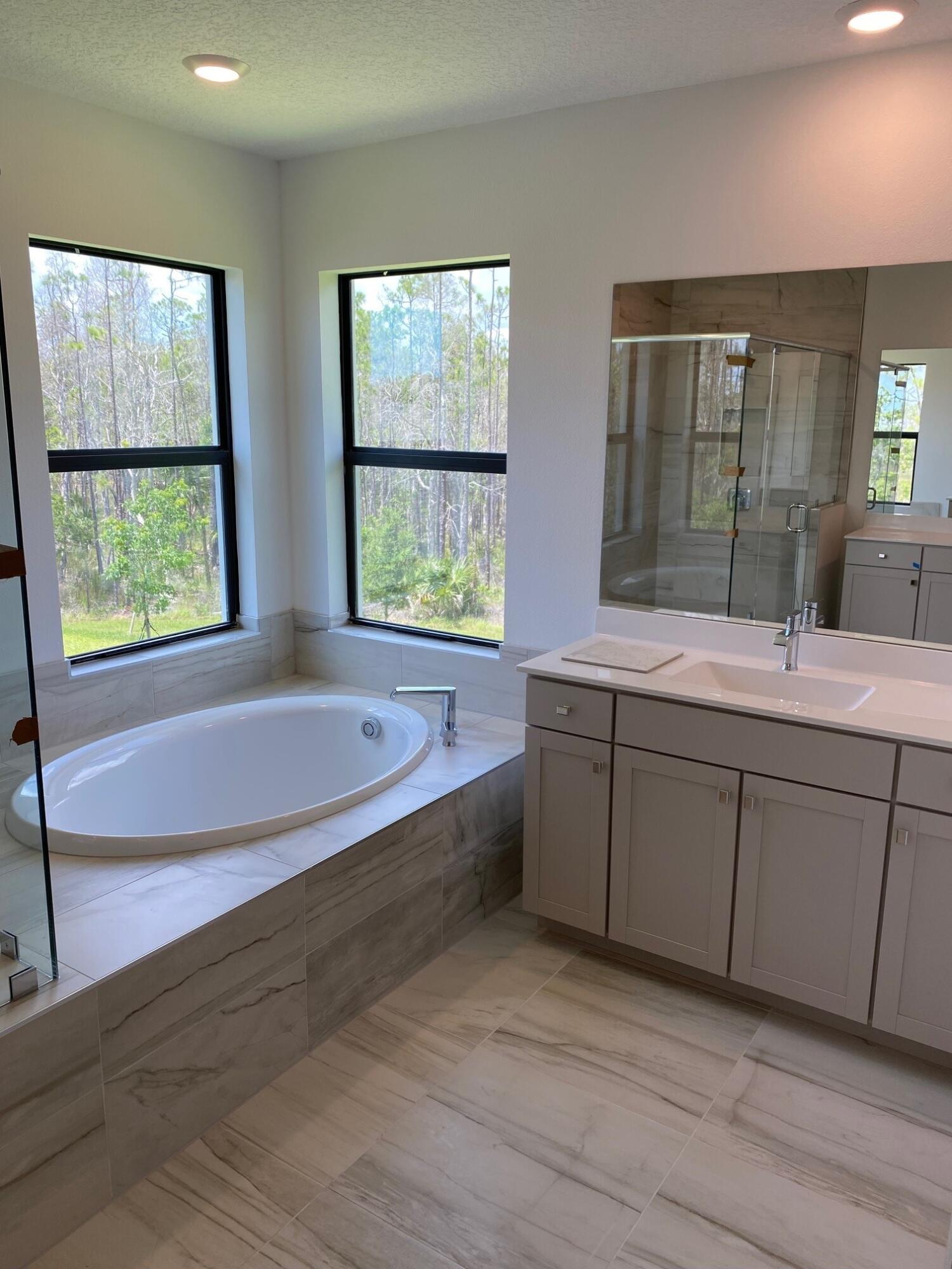 6810 Southeast Park Trace Drive Stuart, FL 34997 - Photo 13 of 21 a spacious bathroom with double vanity a window a bathtub and view