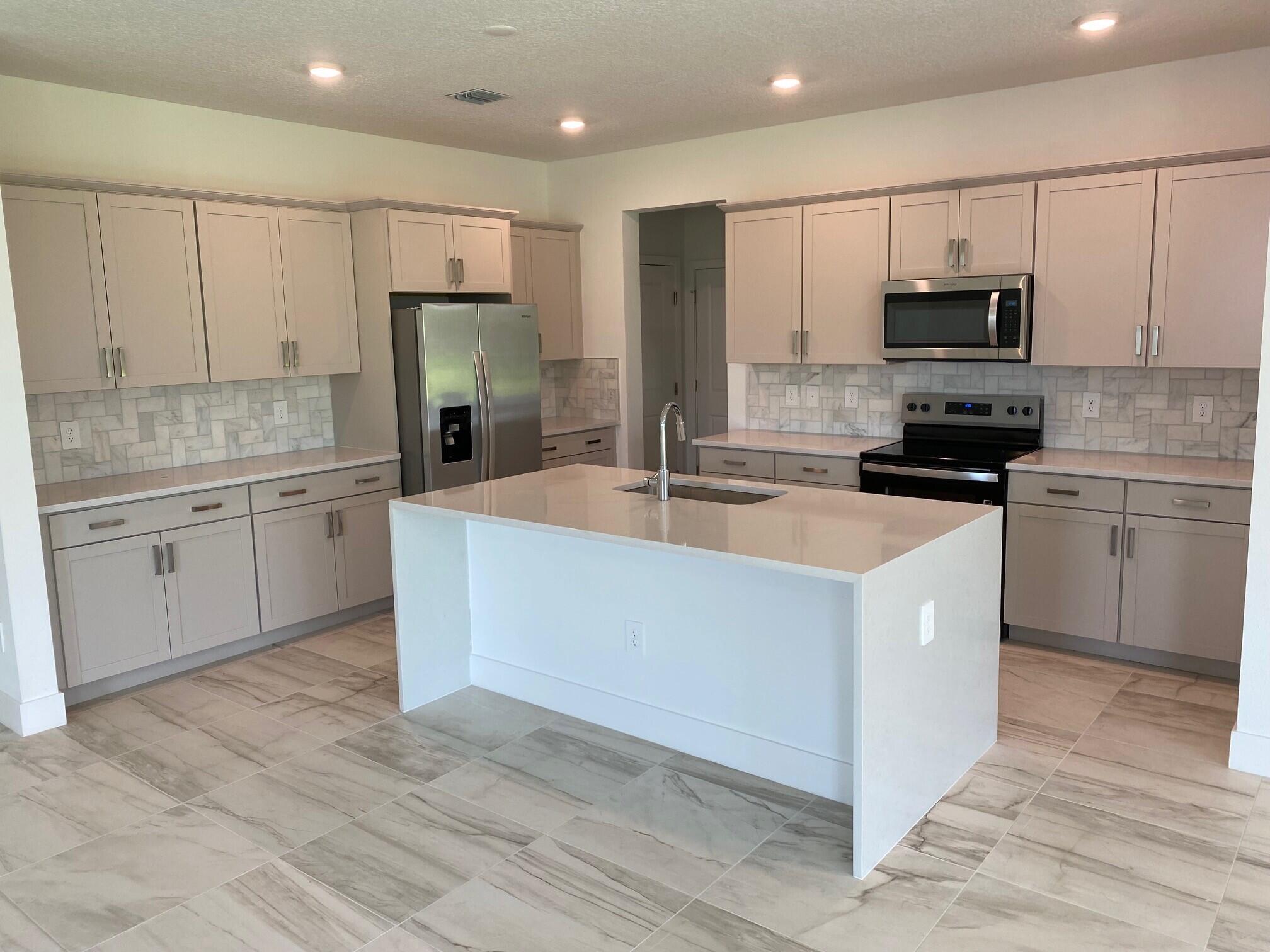 6810 Southeast Park Trace Drive Stuart, FL 34997 - Photo 5 of 21 a kitchen with granite countertop a sink stainless steel appliances and white cabinets