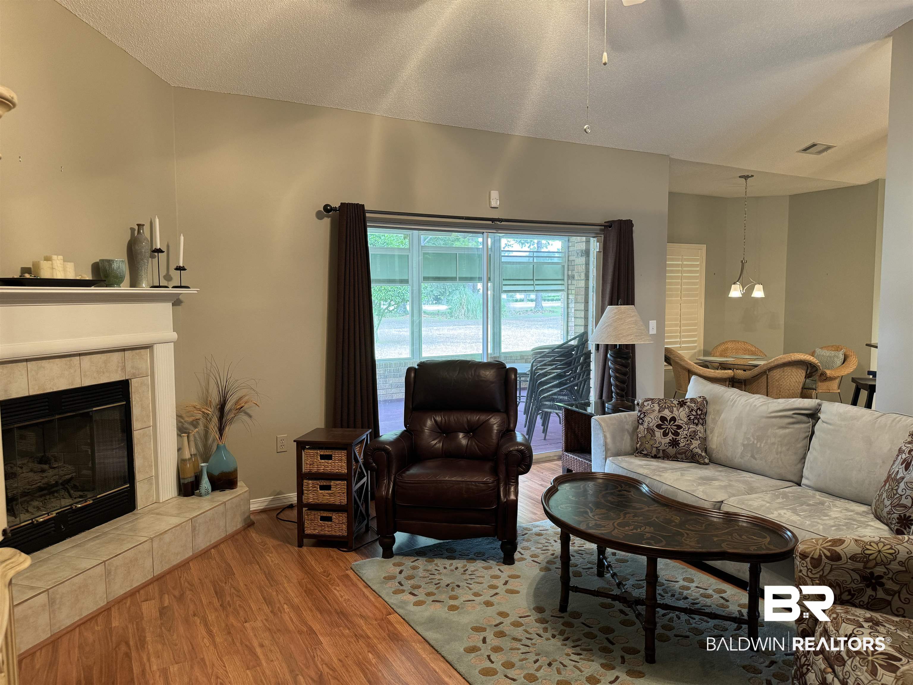 9139 Clubhouse Drive Foley, AL 36535 - Photo 12 of 30 Living room featuring a textured ceiling, an inviting chandelier, wood-type flooring, and a tiled fireplace