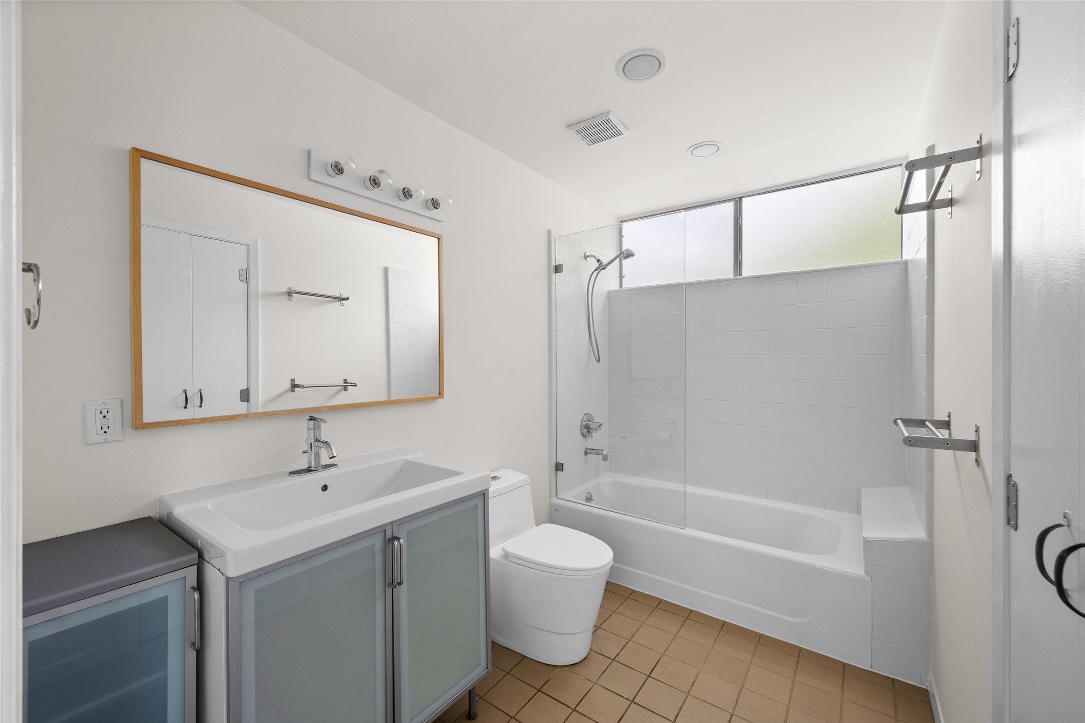 1305 Chestnut Avenue Austin, TX 78702 - Photo 21 of 40 A well-lit primary bathroom features a shower-tub combo, vanity, and ample natural light from an obscured window.