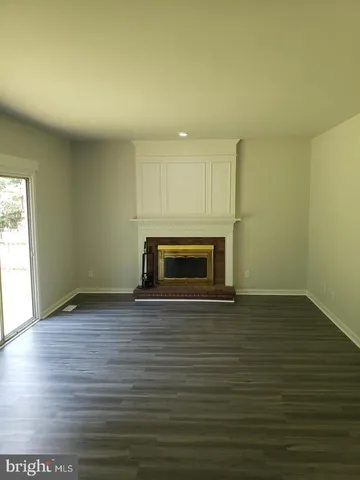 a view of empty room with wooden floor and fireplace