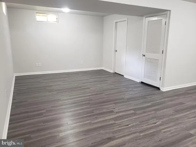 a view of an empty room with wooden floor and closet
