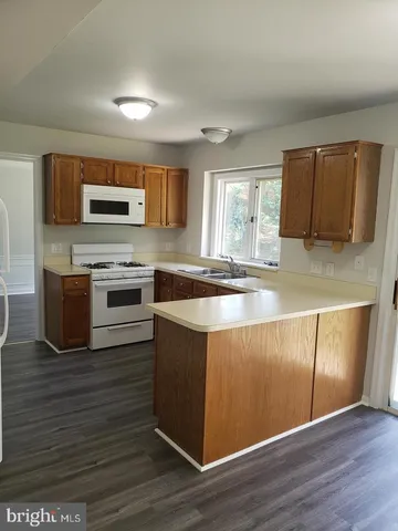a kitchen with kitchen island granite countertop a stove top oven a sink and a microwave