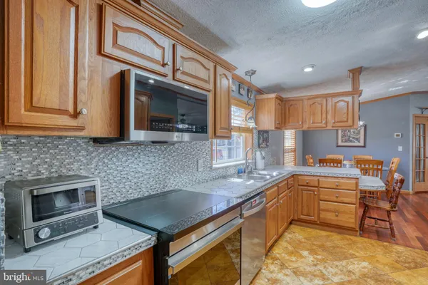 a kitchen with stainless steel appliances granite countertop a refrigerator a stove and a sink with wooden floor