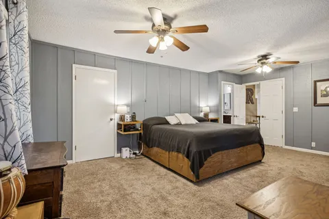 a bedroom with a bed ceiling fan and a wooden floor