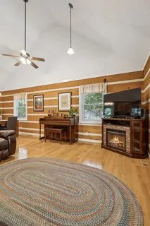 a living room with furniture a flat screen tv and floor to ceiling windows