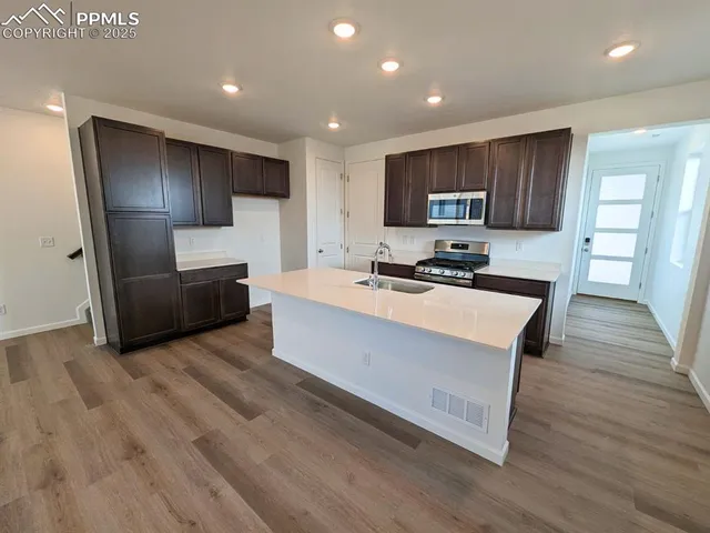 a kitchen with stainless steel appliances kitchen island granite countertop a stove a sink a refrigerator and a microwave