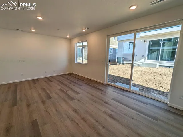 an empty room with wooden floor and windows