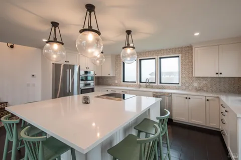 a kitchen with stainless steel appliances a table chairs and white cabinets