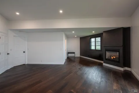 an empty room with wooden floor fire place and windows
