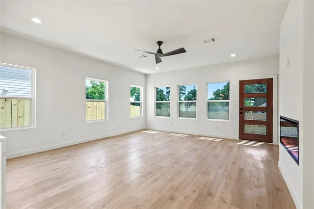 a view of an empty room with a window and wooden floor