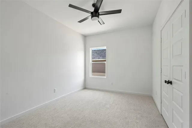 an empty room with a ceiling fan and windows
