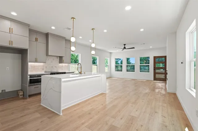 a large kitchen with granite countertop a large counter top a sink stainless steel appliances and cabinets