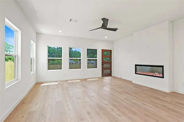 a view of an empty room with a window and wooden floor